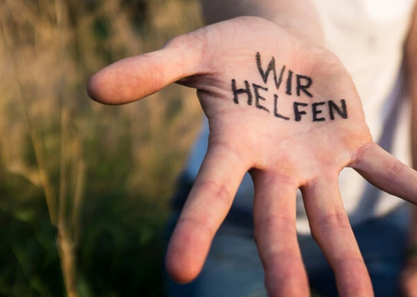 Eine offene Hand mit dem Schriftzug 'WIR HELFEN', die Unterstützung und Hilfe symbolisiert.