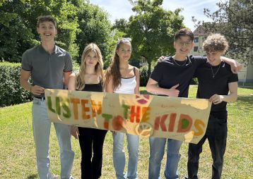 Fünf Jugendliche mit einem Plakat mit der Beschriftung "Listen to the Kids"
